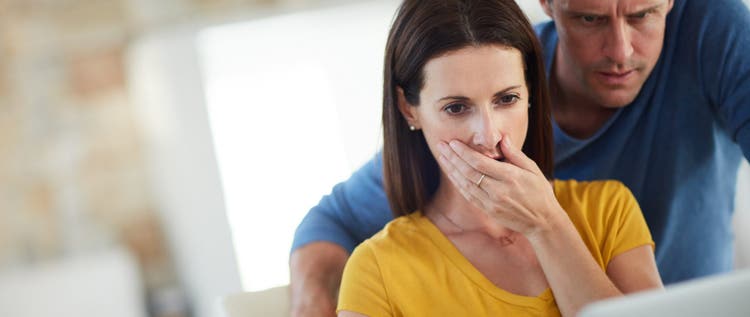 Cropped shot of a mature couple looking shocked while using a laptop together at home