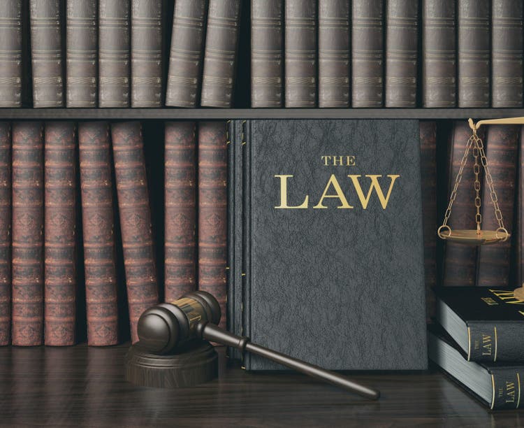 Law bookshelf with wooden judge's gavel and golden scale