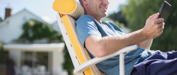 A man relaxing on a chair by a pool, looking at his phone