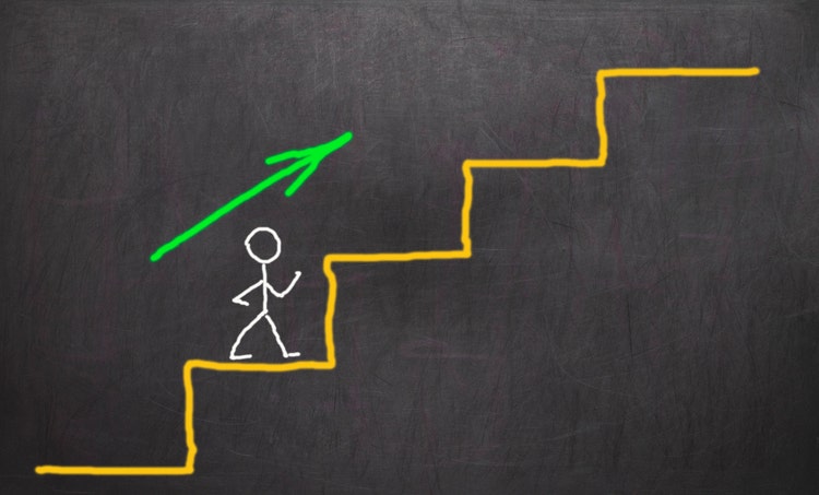 A stick figure person on a chalkboard goint up stairs