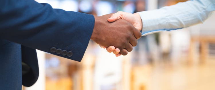 Mid section close-up of diverse Business people shaking hands with each other in corridor at office. International diverse corporate business partnership concept