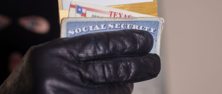 Masked theif steals a victim's identification cards.