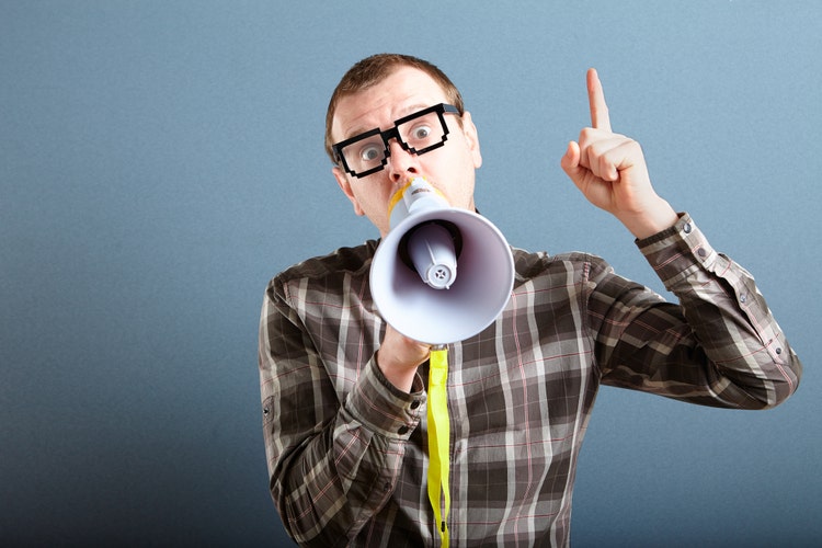 Nerdy guy with glasses holding megaphone and screaming loud, and gesturing with index finger raised