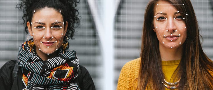 Two young women in front of a biometric face scanner. Artificial intelligence concept.