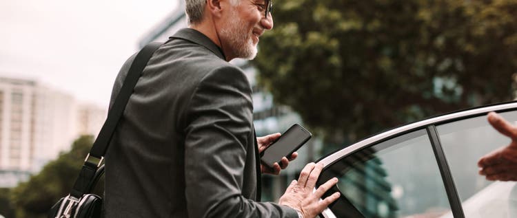 Older man in business suit getting into a waiting car.