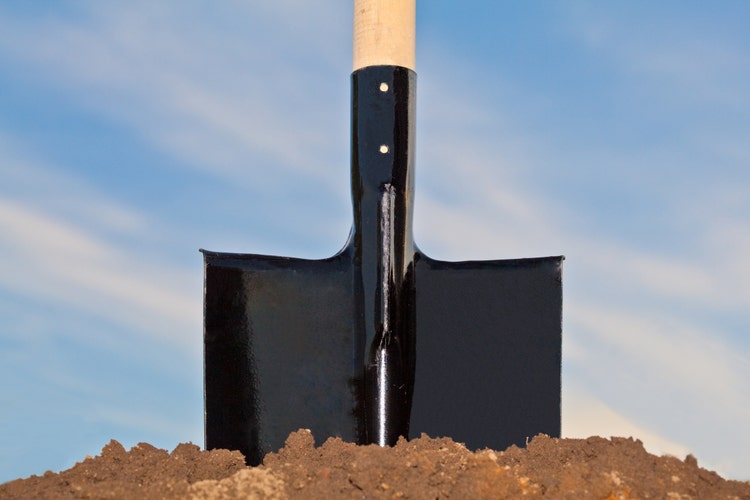 Shovel in the heap of ground against blue sky