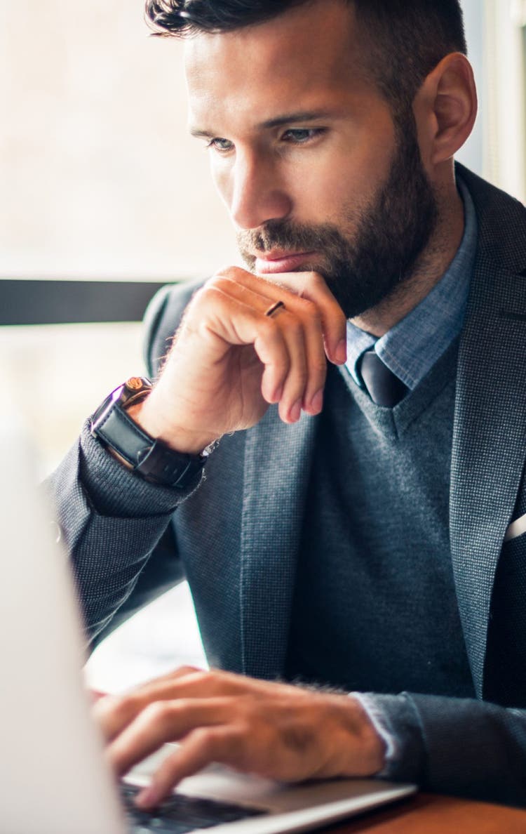 Handsome businessman working on a laptop in a cafe.