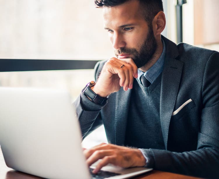 Handsome businessman working on a laptop in a cafe.